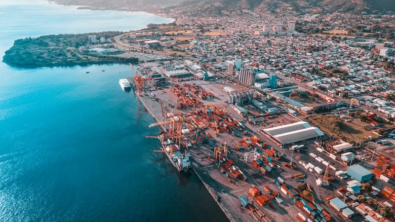 Aerial view of Caribbean port with cargo containers and shipping vessels showing Trinidad and Tobago military agreement and international trade infrastructure