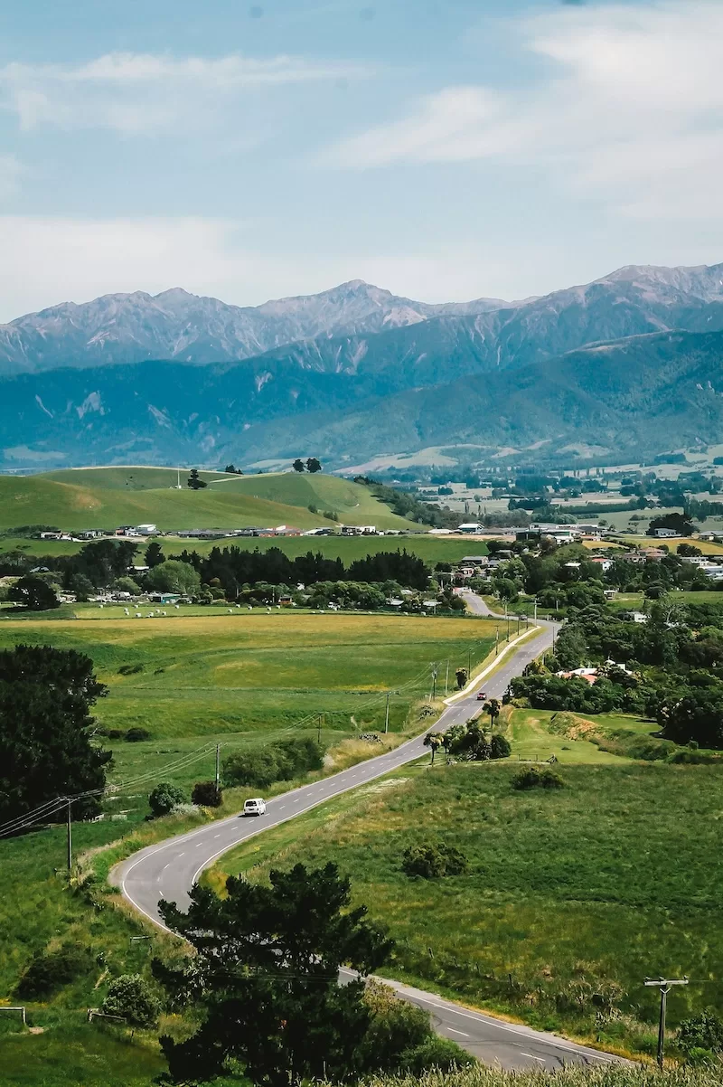 Rolling green hills and snow-capped mountains in New Zealand showing natural beauty and coherent governance environment appealing to expats seeking stability