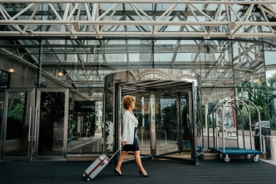 A person works on a laptop with a cup of coffee on a wooden dock, with their dog sitting beside them, embodying the concept of bleisure travel and work-life balance.
