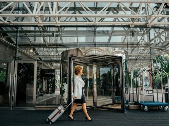 A person works on a laptop with a cup of coffee on a wooden dock, with their dog sitting beside them, embodying the concept of bleisure travel and work-life balance.