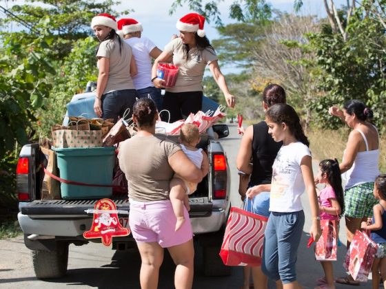 Expat community celebrating Christmas with local Costa Rican families in rural town, sharing gifts and traditions from pickup truck