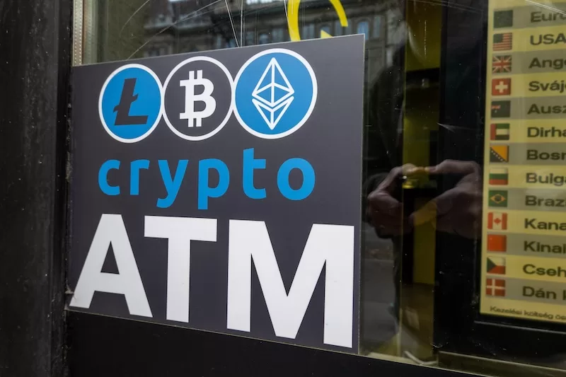 Cryptocurrency ATM sign displaying Bitcoin, Ethereum, and Litecoin logos at a convenience store, representing crypto fraud risks and digital currency accessibility
