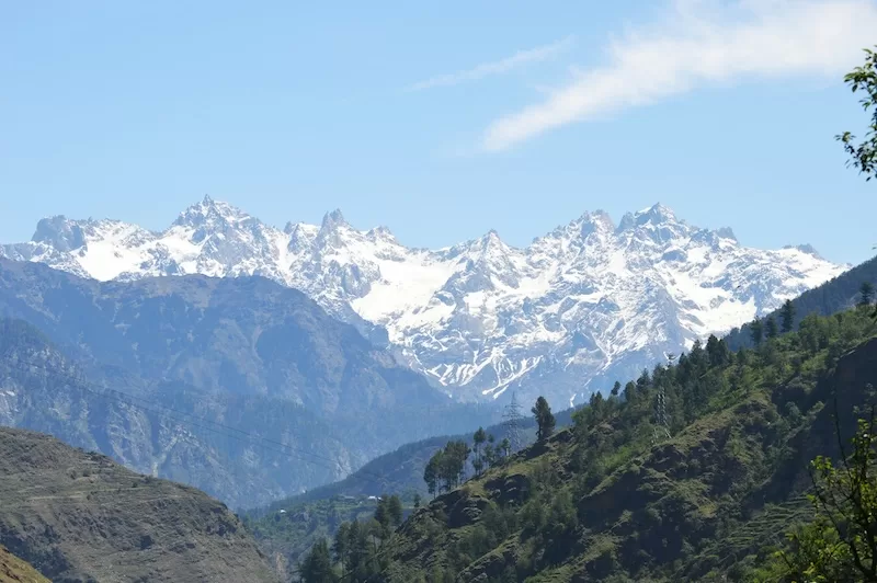 Snow-capped Himalayan mountain range with forested valleys, representing the region where China is constructing a massive hydropower project with environmental concerns