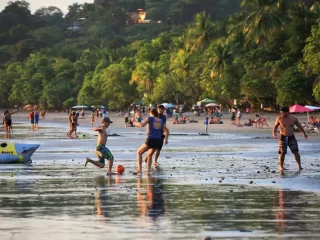 Families and children playing soccer and enjoying beach activities together in Costa Rica, demonstrating community bonding and social connection