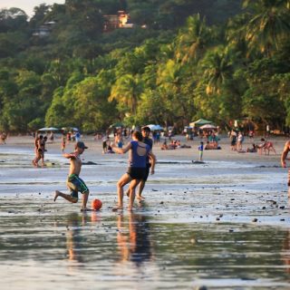 Families and children playing soccer and enjoying beach activities together in Costa Rica, demonstrating community bonding and social connection