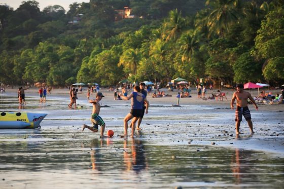 Families and children playing soccer and enjoying beach activities together in Costa Rica, demonstrating community bonding and social connection
