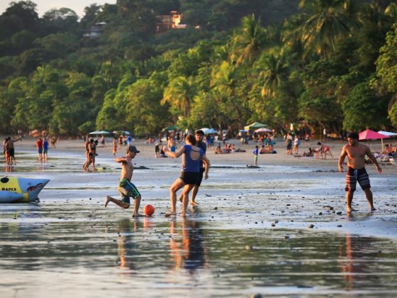 Families and children playing soccer and enjoying beach activities together in Costa Rica, demonstrating community bonding and social connection