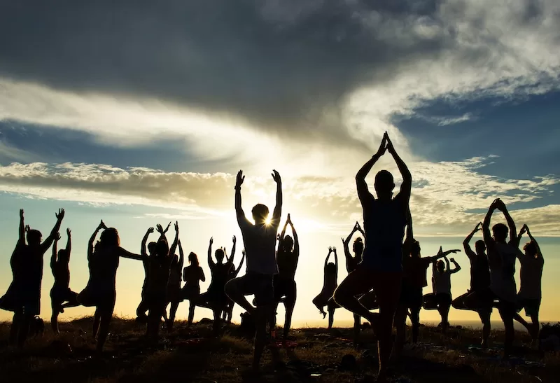 Group of expats practicing yoga and meditation together at sunset in Costa Rica, showing wellness community building and mindfulness activities