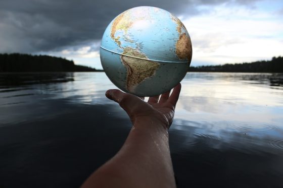 Hand holding a globe over calm water, symbolizing global mobility and building a second legal home across international borders