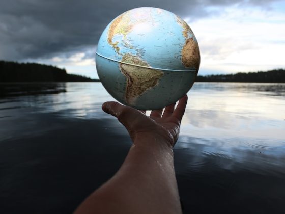 Hand holding a globe over calm water, symbolizing global mobility and building a second legal home across international borders