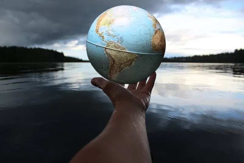 Hand holding a globe over calm water, symbolizing global mobility and building a second legal home across international borders