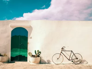 White Mediterranean-style building with green arched door and potted cactus plants, representing the lifestyle and independence offered by global property ownership