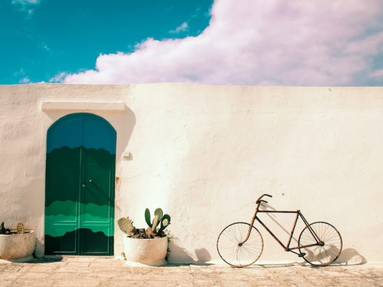 White Mediterranean-style building with green arched door and potted cactus plants, representing the lifestyle and independence offered by global property ownership