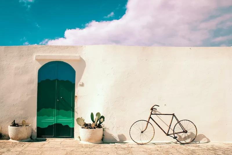 White Mediterranean-style building with green arched door and potted cactus plants, representing the lifestyle and independence offered by global property ownership