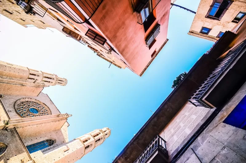 Upward view of historic pink and cream buildings with ornate architecture and blue sky showing Mediterranean charm appealing to expats in Southern Europe