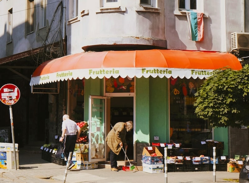 Life begins at street level. Produce stacked in crates. Sun on the awning. A budget that smiles back at you while you shop.