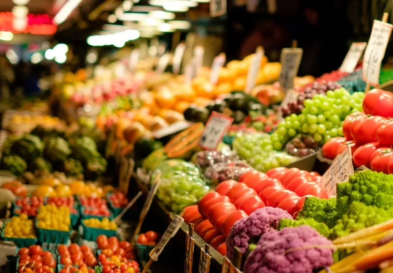 Vibrant farmers market display with fresh produce including tomatoes, leafy greens, and colorful vegetables, representing local community integration and lifestyle benefits of establishing a second legal home