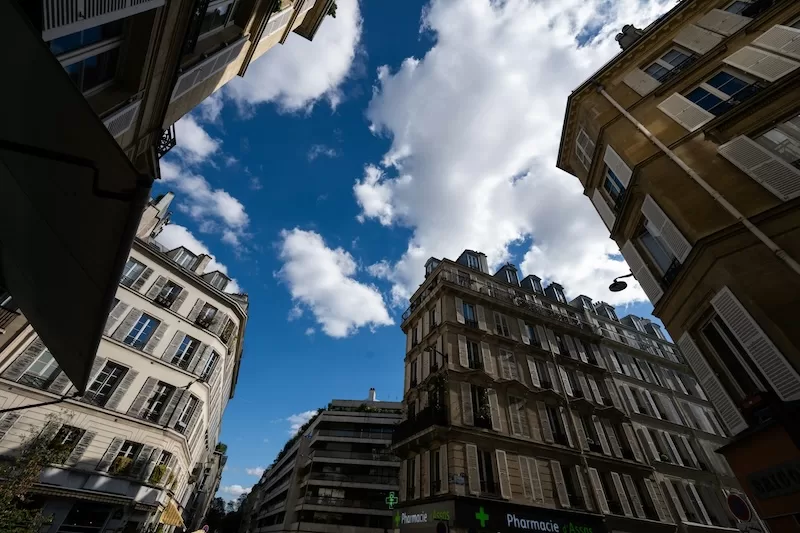 Upward view of Parisian apartment buildings with classical architecture and blue sky, representing European urban living and second legal home opportunities in established cities