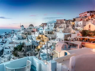 Iconic Mediterranean white and pink buildings at sunset with blue domes showing Greece's architectural beauty and appeal for expats seeking low-tax living