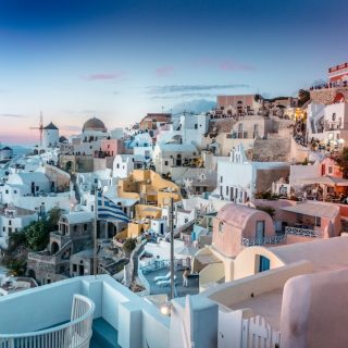 Iconic Mediterranean white and pink buildings at sunset with blue domes showing Greece's architectural beauty and appeal for expats seeking low-tax living