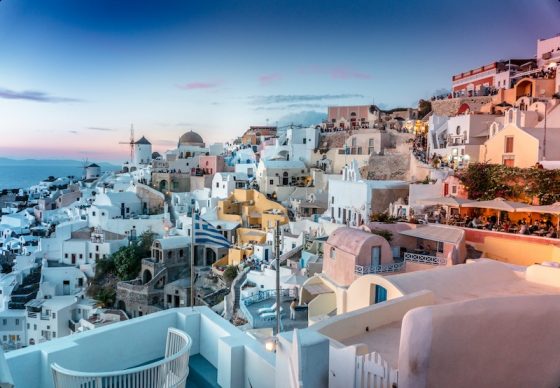 Iconic Mediterranean white and pink buildings at sunset with blue domes showing Greece's architectural beauty and appeal for expats seeking low-tax living