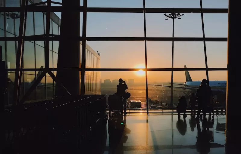 Airport terminal at sunrise with travelers and aircraft showing international travel and global mobility for expats managing tax residency across borders