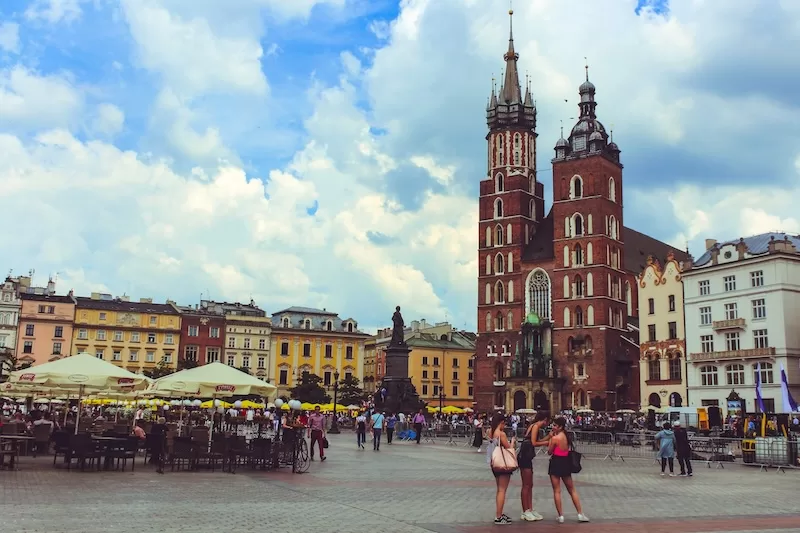 Kraków Poland historic market square with red brick church and colorful buildings showing affordable Eastern European city for stable living
