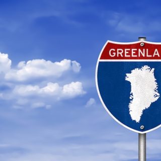 A highway sign with an outline of Greenland, symbolizing the geopolitical pressure from the U.S. and its impact on international news and relations.