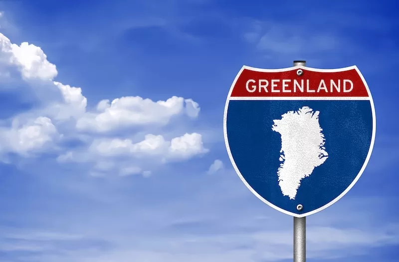 A highway sign with an outline of Greenland, symbolizing the geopolitical pressure from the U.S. and its impact on international news and relations.
