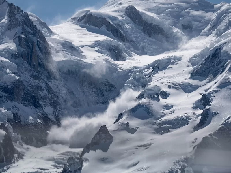 A massive avalanche cascading down a snow-covered mountain in the Austrian Alps, highlighting the peril and recent tragedies in European ski resorts.