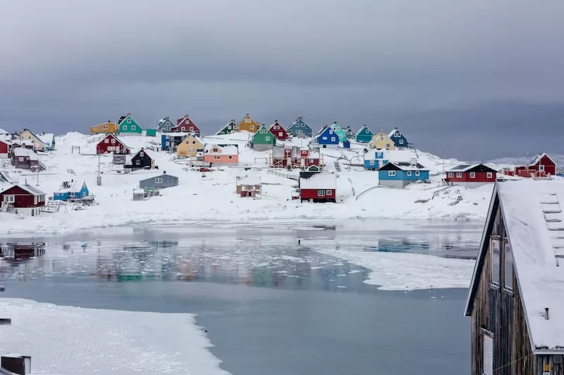 Colorful houses in snowy Greenlandic settlement showing Arctic community and strategic importance of Greenland for geopolitical interests and resources