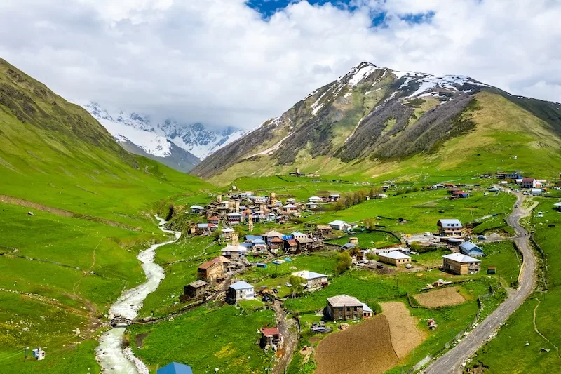 Mountain village in valley with river and snow-capped peaks showing Georgian landscape and Pankisi Valley tourism destination for cultural travelers