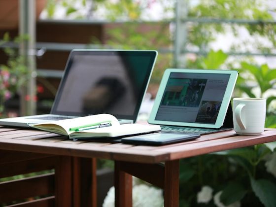 Remote worker with laptop and tablet at outdoor garden desk showing digital nomad lifestyle and location independence for global professionals seeking residency
