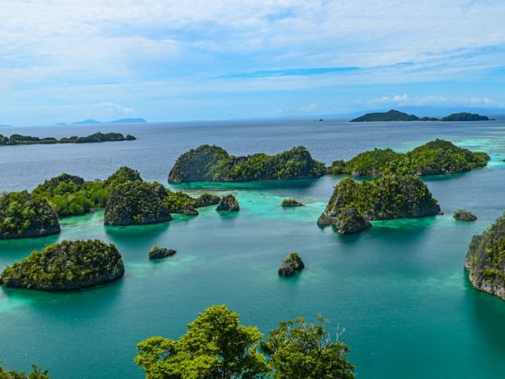 Lush green islands with turquoise water in Raja Ampat, Indonesia, a top destination for sustainable travel on a budget and eco-friendly tourism in Southeast Asia