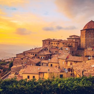 A stunning sunset over the ancient, terracotta-roofed town of Volterra, Italy, a dream location for those considering the country's €1 house experiment.