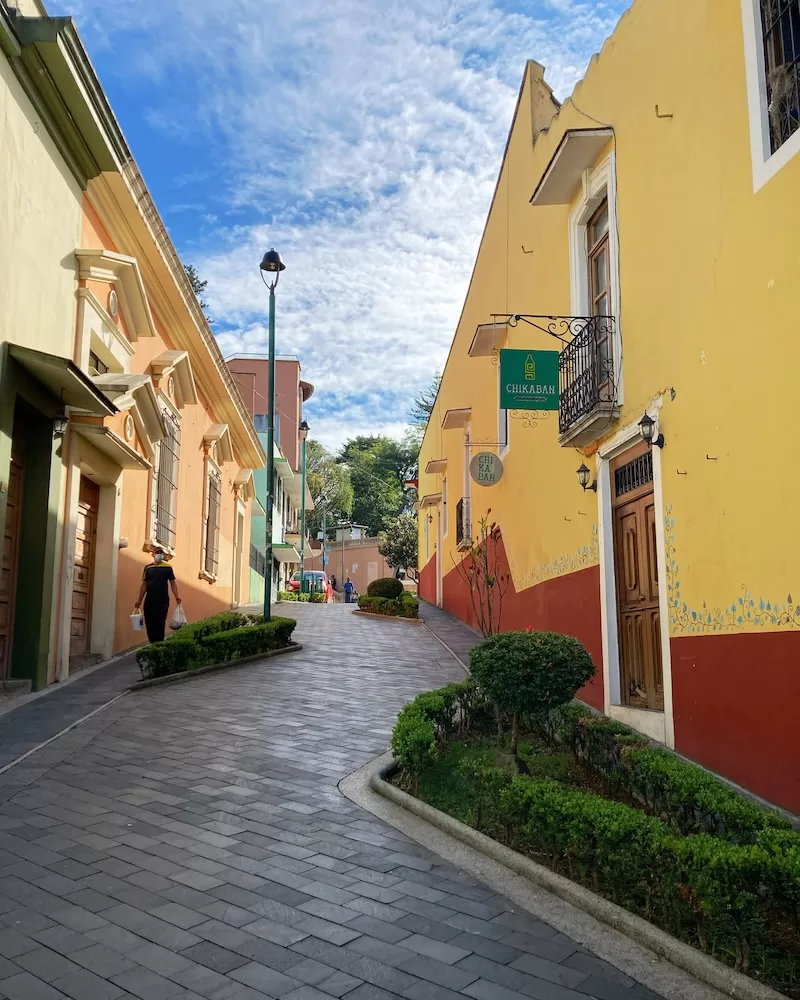 A charming, narrow cobblestone street in Xalapa, Mexico, lined with colorful colonial buildings, showcasing the city's unique and walkable urban landscape.