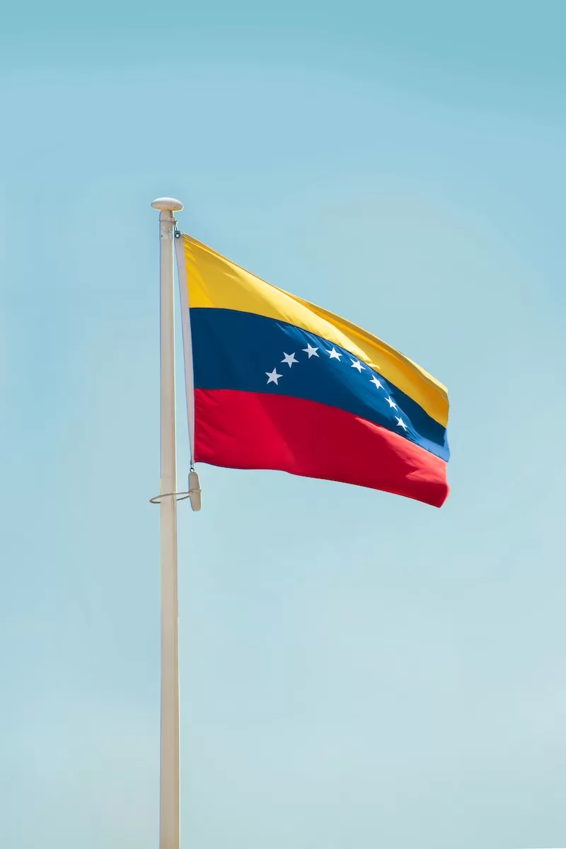 Venezuelan flag waving against clear blue sky symbolizing Venezuela's political crisis and geopolitical tensions following leadership changes and international intervention