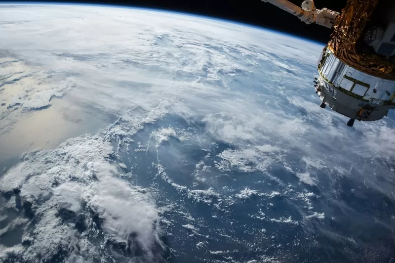 Earth viewed from space with satellite showing planet's atmosphere and clouds illustrating NASA's space exploration and international space station operations