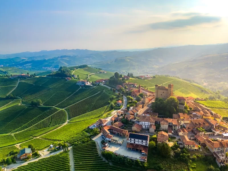 An aerial view of a picturesque Italian village nestled among rolling green vineyards, representing the idyllic lifestyle that draws buyers to the €1 house experiment.