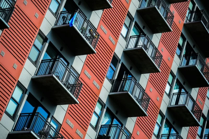 Modern apartment building with red and white facade showing housing pressure and urban density affecting relocation decisions