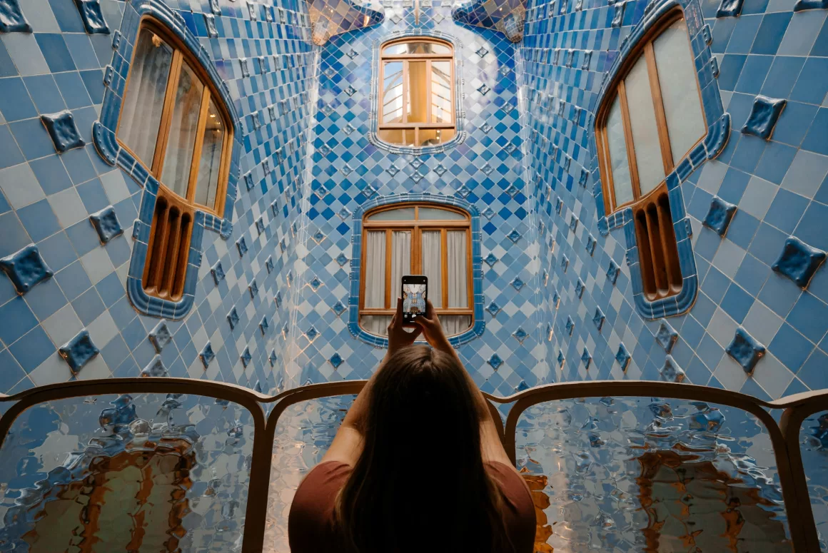 A solo traveler taking a photo of the intricate blue tiles of Casa Batlló in Barcelona, showcasing how solo travel allows for personal exploration of cultural interests.