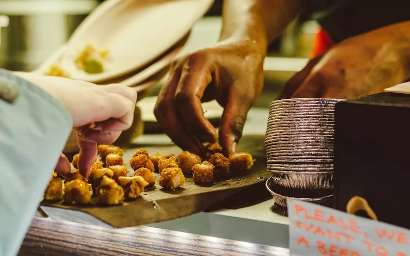 A person receiving a sample of food at a street food stall, an example of the authentic culinary experiences available when you step outside the resort.