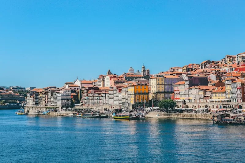 Cascade of colorful 18th-century townhouses in Ribeira neighborhood cascading toward Douro River showing historic charm that attracts expats to Porto Portugal