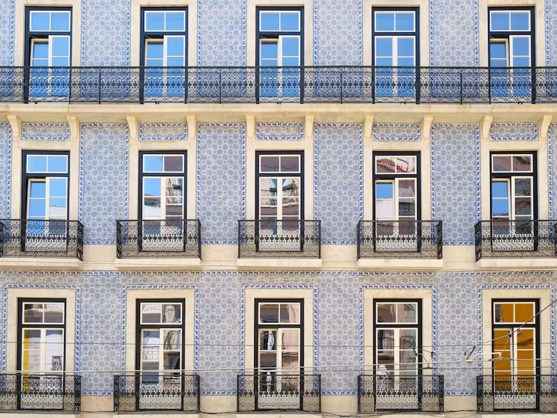 The facade of a building in Lisbon, Portugal, covered in traditional blue Azulejo tiles, showcasing the cultural immersion possible during bleisure travel.