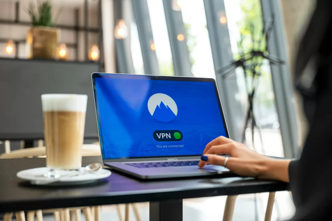 A person using a laptop with a VPN connection screen in a cafe, emphasizing the importance of digital security for remote workers and solo travelers abroad.