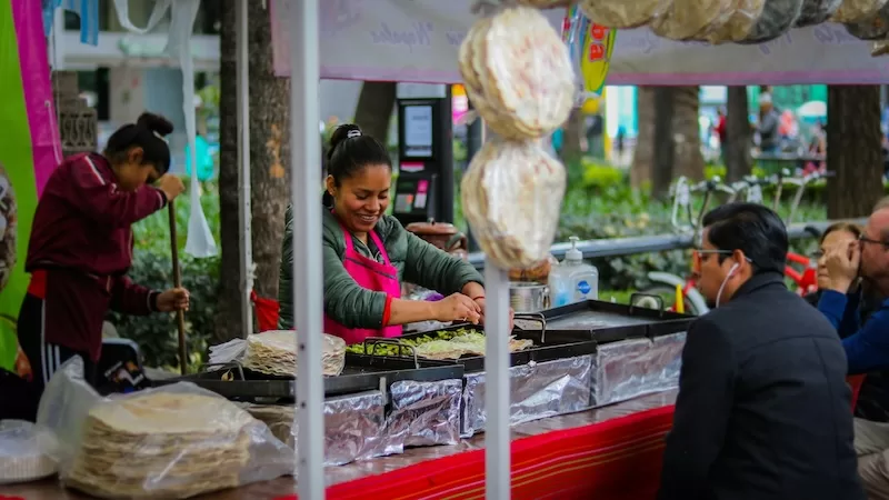 A woman prepares food at a street stall in Mexico City, a vibrant example of how to eat sustainably and affordably by supporting local food vendors