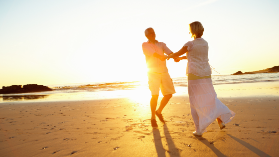 Couple walking together along a sandy beach at sunset enjoying a peaceful seaside moment.
