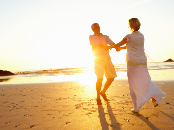 Couple walking together along a sandy beach at sunset enjoying a peaceful seaside moment.