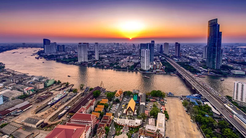 Bangkok skyline at sunset with Chao Phraya River and temples
