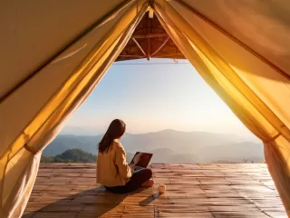 Remote worker with laptop and tablet at outdoor garden desk showing digital nomad lifestyle and location independence for global professionals seeking residency